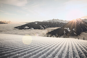 frisch präparierte Pisten in Schladming im Sonnenaufgang, mit Bergen und einer Wolkendecke