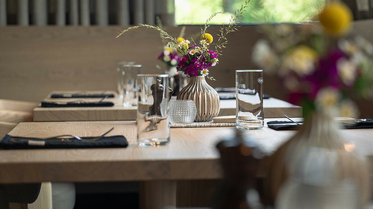 Nahaufnahme eines gedeckten Tisches mit Wassergläsern und Blumen im Restaurant Zirngast